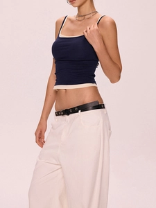 Détail du débardeur bleu marine superposé sur un haut beige avec pantalon large blanc et ceinture