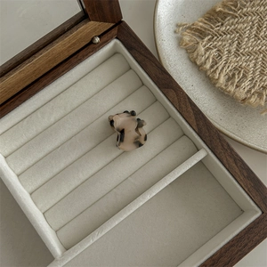 Detail of light leopard print acetate hair claw on a beige velvet jewelry box