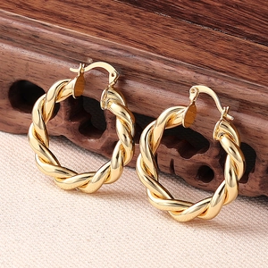 Detail von gedrehten goldenen Creolen mit poliertem Finish auf rustikalem Ständer