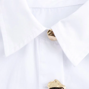 Detail of white shirt collar featuring unique irregular gold metal buttons and premium fabric