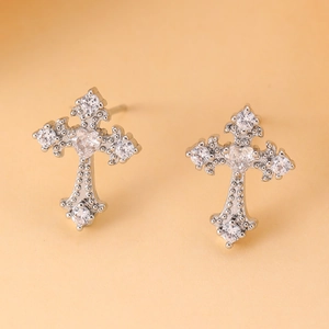 Macro detail of silver cross stud earrings with heart-shaped zircon and pave crystals