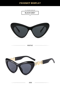 Detail view of black cat eye sunglasses featuring gold heart decorative metal hinges
