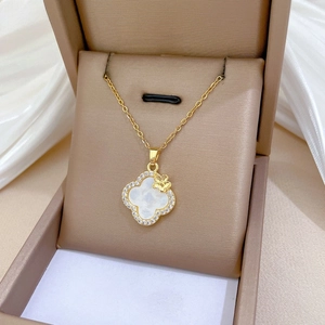 Detailed view of gold clover pendant with pavé crystals and white mother of pearl inlay