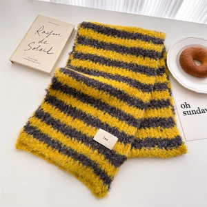 Detail of yellow and black striped wool scarf with ins label on a minimalist desk set