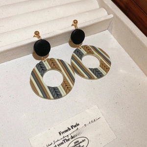Close-up of retro floral clay earrings with wood elements on a jewelry display tray