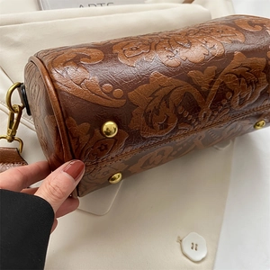 Vintage brown leather cylinder bag featuring floral embossing and bronze hardware details