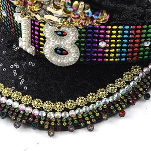 Macro shot of 18th birthday party hat with rainbow rhinestones and golden lace detail
