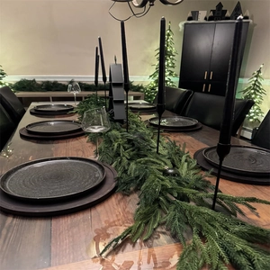 Detail of realistic dark green PE pine garland on a festive dinner table setting