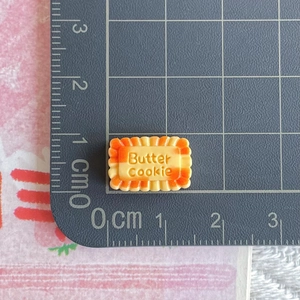 Macro detail of miniature resin butter cookie charm on a scale mat for DIY crafting