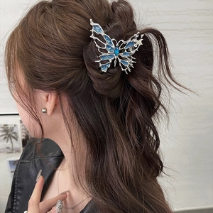 Blue liquid metal butterfly hair claw clip worn by a model in a stylish updo hairstyle