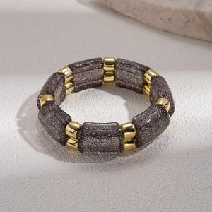 Detail of ethnic acrylic beads with gold glitter and metallic spacers on elastic bracelet
