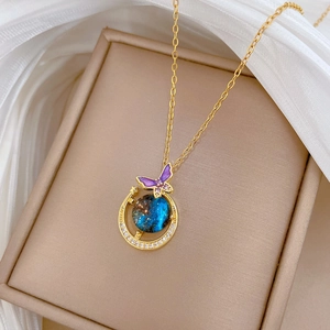 Detailed close-up of a golden necklace with purple butterfly and emerald star pendants