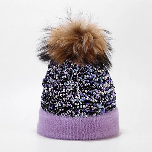 Macro detail of purple knit hat featuring shiny sequins and fluffy brown faux fur pompom
