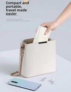 Portable white EVA raincoat being tucked into a shoulder bag for convenient travel