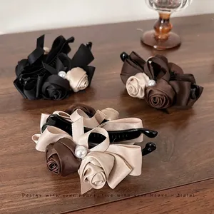 Three elegant vintage rose pearl banana hair clips in black, brown, and cream silk