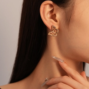 Close-up of butterfly earrings with gold plating and leopard print dots on a model