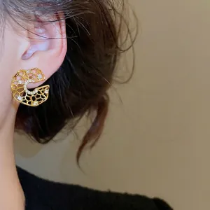 Golden C-shaped hollow mesh earrings with white zircons on a model for a vintage look