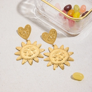 Vue détaillée des boucles d'oreilles soleil et cœur dorées avec visages en relief