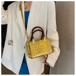 Macro shot of gold crocodile texture handbag with glossy finish and brown resin handles