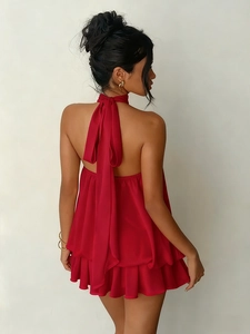 Back view of a red chiffon halter dress with a large bow and layered ruffle hem details
