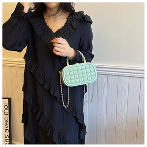 Detail of mint green woven box bag with gold metal handle and chain strap on model