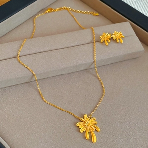 Macro shot of gold-plated palm tree necklace and earrings set in a velvet jewelry tray