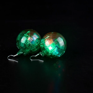 Close-up of green faceted disco ball earrings with vibrant laser reflective light effects