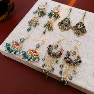Detail view of retro ethnic earrings with zirconia, pearls, and tassels on a display stand
