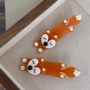 Pair of orange fox-shaped acetate hair clips on a minimalist tray background