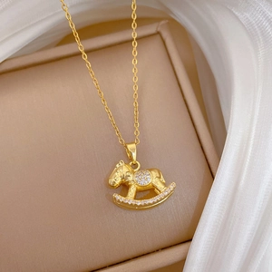 Elegant gold rocking horse necklace with sparkling white zircons on a white silk background