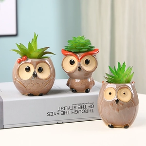 Three owl-shaped ceramic succulent pots with artificial plants on a desk