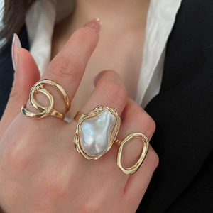 Detailed close-up of golden pearl ring and hollow geometric ring on a model's hand