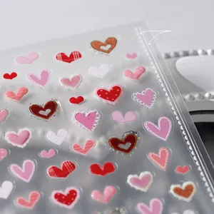 Macro detail of 3D heart nail stickers with gold foil and lace patterns on PVC film