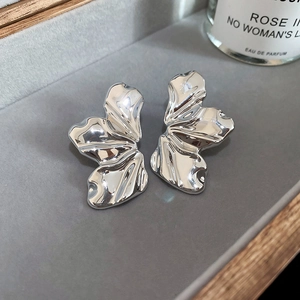 Macro detail of silver-toned irregular petal earrings with textured mirror finish
