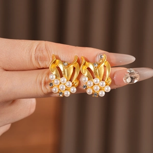 Close-up of golden leaf earrings with white pearls and sparkling zircon accents
