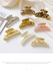 Collection of eight acetate hair claws in tortoise shell and marble patterns displayed on silk