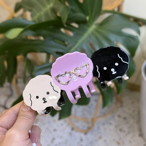 Detailed view of three cute acetate dog-shaped hair claws in white, pink, and black