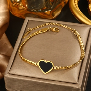 Detail of gold titanium heart bracelet with black enamel inlay on snake chain