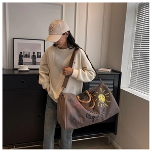 Lifestyle shot of a grey graffiti printed travel bag with adjustable strap on a shoulder