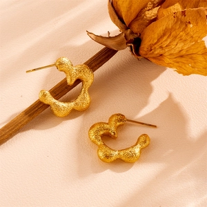 Detailed macro view of gold matte stainless steel floral earrings with hammered texture