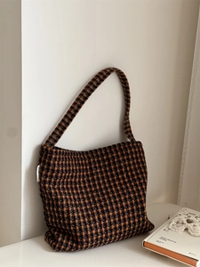 Detail of vintage plaid tweed shoulder bag with vibrant woven texture and side label
