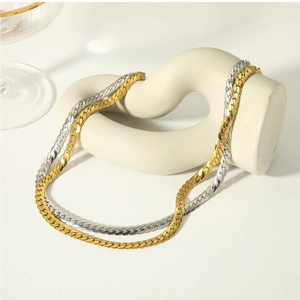 Detailed close-up of gold and silver herringbone chains on a white sculpture