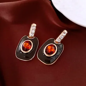 Boucles d'oreilles vintage avec pierre orange et émail noir sur fond en soie rouge