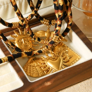 Detailansicht der goldenen Sonnen- und Herzanhänger an einer Kordel mit Leopardenmuster