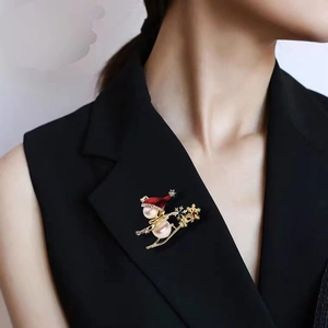 Close-up of pearl snowman brooch with red hat worn on a black sleeveless top
