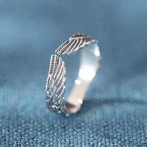 Macro shot of silver feather ring showing detailed wing texture and adjustable open band
