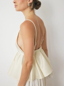 Detail of satin camisole showing open back design and ruffled hem in cream color