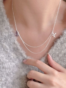 Close-up of minimalist double-layered 925 silver necklace with bird pendant on a sweater
