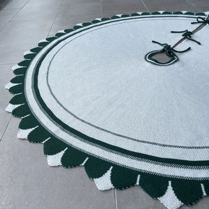 Dettaglio del tappeto per albero di Natale in maglia bianco e verde con bordi ondulati