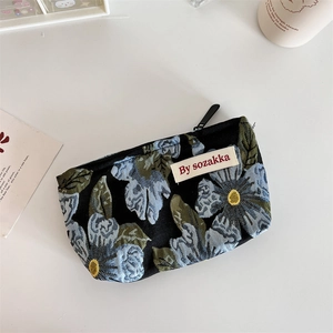 Detail view of black floral fabric pouch with blue flowers and woven brand label